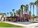 Well-maintained community playground with colorful equipment, picnic areas, and tropical palm trees at 66 John Stuart Mill St, Henderson, NV 89002