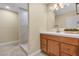 Elegant bathroom featuring a wooden cabinet, sink, decorative mirror, and a luxurious tiled shower with modern fixtures at 7604 Charles Conrad Cir, Las Vegas, NV 89145