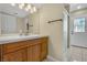 Well-lit bathroom featuring wood cabinets, a white countertop, a glass shower, and access to the backyard at 7604 Charles Conrad Cir, Las Vegas, NV 89145