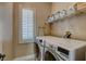 Convenient laundry room featuring a side-by-side washer and dryer, storage shelves, and a bright window at 8022 Severn Valley St, Las Vegas, NV 89139