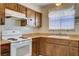 Well-lit kitchen with wood cabinetry, white appliances, and a window over the sink providing ample natural light at 804 S Mallard St, Las Vegas, NV 89107