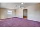 Bright living room with purple carpet, ceiling fan, and natural light from a window at 804 S Mallard St, Las Vegas, NV 89107