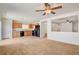 Spacious living room with kitchen view featuring neutral carpet, black appliances, and light wood cabinets at 8626 Anderson Dale Ave, Las Vegas, NV 89178
