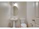 Well-lit powder room featuring a pedestal sink and toilet with a classic oval mirror at 8626 Anderson Dale Ave, Las Vegas, NV 89178