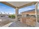 Covered outdoor kitchen with a built-in grill, stone accents, and views of the surrounding neighborhood at 904 Rhyolite Ter, Henderson, NV 89011
