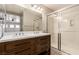 Modern bathroom with double sinks, wood vanity, and glass-enclosed shower at 9773 Bedstraw St, Las Vegas, NV 89178