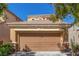A beige two-story home featuring a large two-car garage with a brown door and manicured front yard at 9773 Bedstraw St, Las Vegas, NV 89178