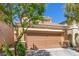 Beige two-story home with a large two-car garage, complemented by mature trees at 9773 Bedstraw St, Las Vegas, NV 89178