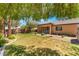 Manicured backyard with a green lawn, mature trees, and a covered patio area perfect for outdoor entertaining at 9812 Turtle Walk Ave, Las Vegas, NV 89149