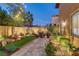 Landscaped backyard with putting green, lush plantings, mature shade trees, and a stone-paved patio at 1272 Olivia Pkwy, Henderson, NV 89011