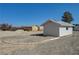 View of multiple outbuildings and a circular concrete barrier on a gravel lot under clear blue sky at 1450 Fern St, Pahrump, NV 89060