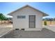 Exterior view of a detached outbuilding with white siding, a gray door, and concrete footings at 1450 Fern St, Pahrump, NV 89060