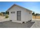 Exterior view of a detached outbuilding featuring white siding, a gray door, and concrete footings at 1450 Fern St, Pahrump, NV 89060