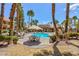 Outdoor pool with a lounge area and tables, surrounded by palm trees and well-maintained landscaping at 2120 Ramrod Ave # 513, Henderson, NV 89014