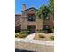 Beige two-story home featuring a balcony, landscaped yard, and tile roof under a bright blue sky at 3450 Erva St # 167, Las Vegas, NV 89117