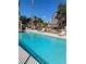 Expansive community pool with lounge chairs and lush palm trees against a clear blue sky at 3450 Erva St # 167, Las Vegas, NV 89117