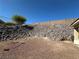 Landscaped backyard featuring a rock wall and partial view of the covered patio at 3567 Cottage Stream Ct, Laughlin, NV 89029