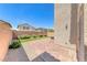 A well-kept backyard featuring faux grass, stone pavers, mature landscaping, and a retaining wall at 358 Badinerie St, Henderson, NV 89011