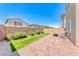 A well-kept backyard featuring faux grass, stone pavers, mature landscaping, and a seating area at 358 Badinerie St, Henderson, NV 89011