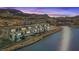 Modern waterfront home with balconies overlooks the scenic lake and mountains at sunset at 36 Lakefront Dr, Henderson, NV 89011