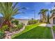 Lush lawn and landscaping in backyard with manicured bushes, trees and stone border at 3636 Chelsea Gardens Dr, Las Vegas, NV 89135