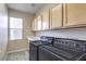 Well-equipped laundry room with modern washer and dryer units, ample cabinet space, and natural light from the window at 3636 Chelsea Gardens Dr, Las Vegas, NV 89135