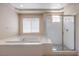 Serene main bathroom featuring a luxurious soaking tub, a glass-enclosed shower, and a bright window at 3636 Chelsea Gardens Dr, Las Vegas, NV 89135
