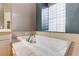 Relaxing soaking tub with tile surround and decorative glass block window for natural light at 5193 N Miller Ln, Las Vegas, NV 89149
