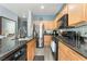 Modern kitchen featuring oak cabinets, stainless steel appliances, and light gray, wood-look flooring at 6270 Dartington Hall St, Henderson, NV 89011