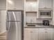 Close up of kitchenette with stainless steel refrigerator, microwave and white cabinets at 6280 Lamont Hills Ave, Las Vegas, NV 89139