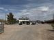 View of the front of the home with a large dirt lot and several cars parked at 664 Spring Rd, Indian Springs, NV 89018
