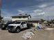 Angle shot of the two-story home, showing the dirt front yard and vehicles in the driveway at 664 Spring Rd, Indian Springs, NV 89018