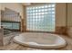 Inviting bathroom with marble fireplace, jetted tub, and glass block window at 7969 Bermuda Dunes Ave, Las Vegas, NV 89113
