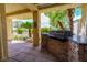Enjoy grilling on this outdoor kitchen with a stone backsplash, under a covered patio lined with palm trees at 7969 Bermuda Dunes Ave, Las Vegas, NV 89113