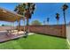 Backyard features palm trees, a covered patio area with decorative lighting, small area of artificial turf, and privacy wall at 8039 Baldy Mountain Ave, Las Vegas, NV 89131