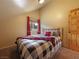 Bedroom featuring a wooden bed frame, a plaid blanket, and a window with red curtains at 855 E Ponderosa Rd, Mammoth Creek, UT 84735