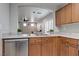 Bright kitchen area with stainless steel dishwasher, wooden cabinets, and a view to living room at 9100 Balcony Trellis Ave, Las Vegas, NV 89149