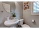 Cozy powder room features a pedestal sink, round mirror, and plantation shutters for natural light at 9100 Balcony Trellis Ave, Las Vegas, NV 89149