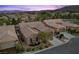 A dusk aerial view shows the desert-landscaped homes in a suburban neighborhood near the mountains at 940 Viscanio Pl, Las Vegas, NV 89138