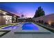 A backyard pool and spa feature led lighting and outdoor lounge area under the darkening sky at 940 Viscanio Pl, Las Vegas, NV 89138