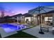 Backyard pool with tanning ledge, patio and artificial turf, with indoor/outdoor living space, at dusk at 940 Viscanio Pl, Las Vegas, NV 89138