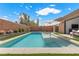 Backyard pool with tanning ledge, patio and artificial turf, and brick wall at 940 Viscanio Pl, Las Vegas, NV 89138
