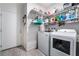 Bright laundry room featuring white washer, dryer, white door, tile floor, and built-in shelving for storage at 9565 Camelback Creek Dr, Las Vegas, NV 89178