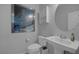 Small half-bath with a pedestal sink, framed art, round mirror and a stylish design at 12311 Middle Creek St, Las Vegas, NV 89138