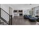 Bright living room featuring stairs with black banister, grey hardwood floors, and open layout to kitchen at 12311 Middle Creek St, Las Vegas, NV 89138