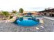 Wide shot of the backyard pool with spa, rock features, palm trees, and an umbrella covered seating area at 1500 Tumbleweed Dr, Henderson, NV 89002