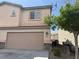 Two-story house featuring a two car garage, desert landscaping, and beige stucco siding at 2105 William Holden Ct, Las Vegas, NV 89142