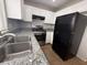 Modern kitchen with stainless steel appliances, granite countertops, white cabinets and a black refrigerator at 2105 William Holden Ct, Las Vegas, NV 89142