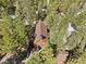 A high-angle view showcases a charming log cabin surrounded by verdant trees with a dark shingled roof at 2160 Via Vita St, Mount Charleston, NV 89124