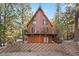 A-frame log cabin featuring a tiered brick patio and an expansive balcony, set amongst tall trees and greenery at 2160 Via Vita St, Mount Charleston, NV 89124
